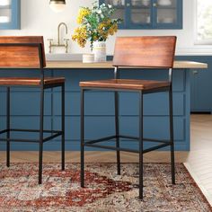 two stools sitting on top of a rug in front of a kitchen island with blue cabinets