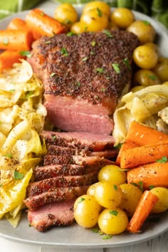 a white plate topped with meat, potatoes and carrots next to other food items