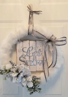 a white door hanger decorated with flowers and ribbon