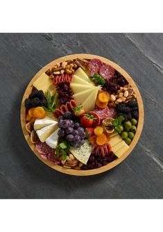 a wooden bowl filled with lots of different types of cheese and meats on top of it