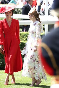 two women in red dresses and hats are standing next to each other on the grass