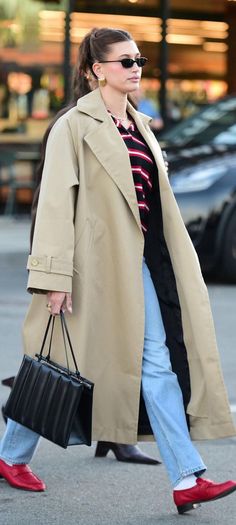 a woman walking down the street with a handbag in her other hand and wearing red shoes