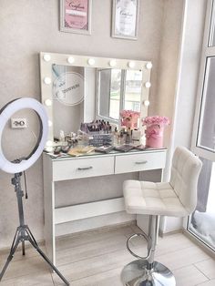 a white vanity with lights on it and a chair in front of the mirror next to it