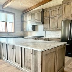 a kitchen with an island in the middle and wooden cabinets on both sides, along with stainless steel appliances