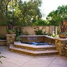 an outdoor hot tub in the middle of a patio with potted plants on either side