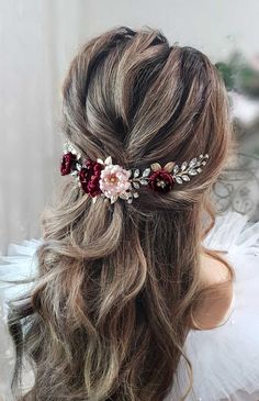 a woman wearing a hair comb with flowers on it's head and long wavy hair