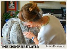 a woman is working on a large pumpkin