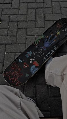 a skateboard is laying on the ground next to someone's pants and shoes