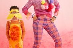 a woman and child in costume standing next to each other on a pink background with fluffy pom poms