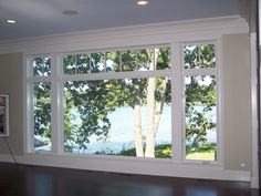 an empty living room with large windows overlooking the water and trees in front of it