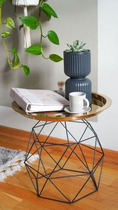 a table with some books and a cup on it next to a potted plant