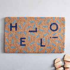 a door mat with the word hello spelled on it and two pairs of sandals next to it