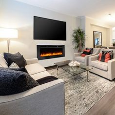 a living room filled with furniture and a flat screen tv mounted on the wall above an electric fireplace