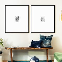 two framed pictures hang on the wall above a wooden bench with pillows and throw pillows