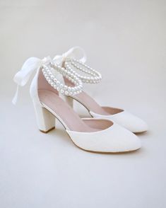 a pair of white shoes with pearls on the heel