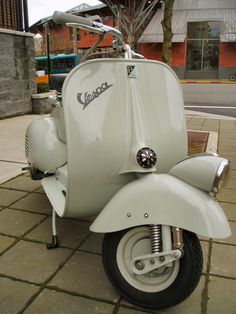 a white scooter is parked on the sidewalk