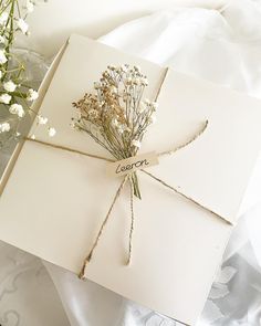 an open card with flowers tied to it on a white blanket next to a bouquet of baby's breath