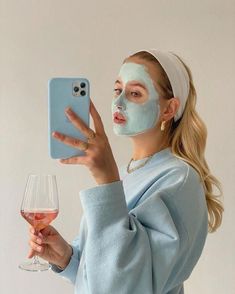 a woman is holding up her cell phone to take a selfie with the face mask on