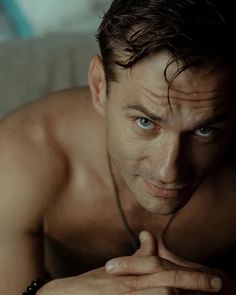 a shirtless man with blue eyes and no shirt on is looking at the camera