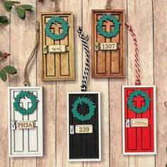 four doors decorated with wreaths and christmas decorations on top of a wooden table next to candy canes