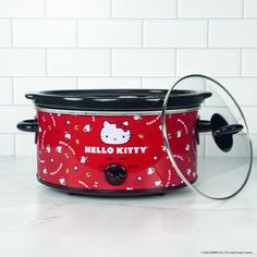 a hello kitty crock pot with lid on a white counter next to a brick wall