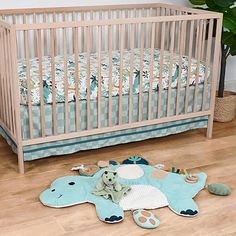 a baby crib with a stuffed animal on the floor next to it and a potted plant