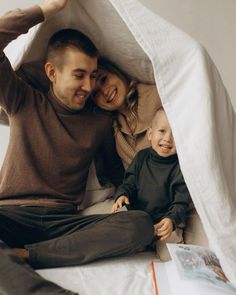 a man, woman and child are sitting in a tent