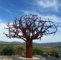 a large metal tree sculpture sitting on top of a cement wall