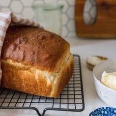 a loaf of bread sitting on top of a cooling rack next to a bowl of butter