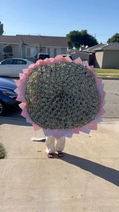 a person walking down the street with an umbrella made out of flowers on their head