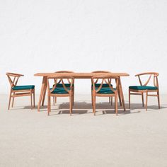 three chairs and a table in front of a white wall with blue cushions on it