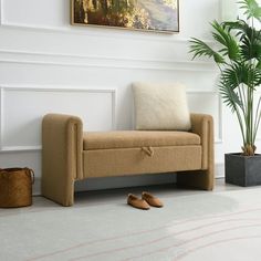 a beige couch sitting next to a potted plant