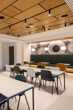 an empty classroom with desks and chairs in front of a large mural on the wall