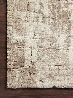 a white rug on top of a wooden floor next to a brown and white wall