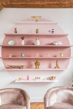 two chairs in front of pink shelves with figurines on them