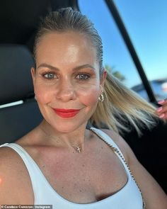 a woman sitting in the back seat of a car with red lipstick on her lips