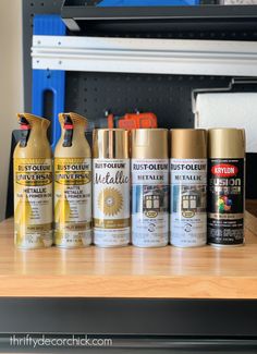 several different types of spray paint sitting on a table next to a toolbox with tools in it