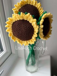 two crocheted sunflowers in a vase on a window sill