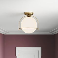 an empty room with purple walls and a white door in the center is lit by a round light fixture