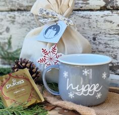 a coffee mug sitting on top of a table next to a bag and some pine cones