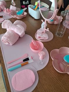 a wooden table topped with lots of pink bathroom accessories and decorating utensils