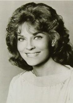 an old black and white photo of a woman with curly hair smiling at the camera