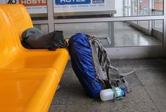 luggage sitting on the ground in front of a yellow bench with a blue bag next to it