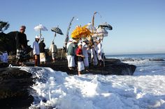 a group of people standing next to each other on top of snow covered rocks near the ocean