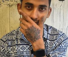 a man with a tattoo on his arm is looking at the camera while holding his hand to his face