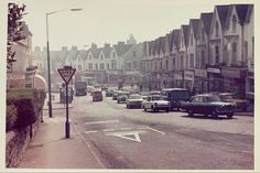 an old photo of cars driving down the street