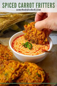 a person dipping some food into a bowl with red sauce on it and corn stalks in the background