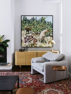 a living room filled with furniture and a painting hanging on the wall over a fire place