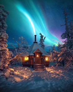 a cabin in the woods with an aurora bore above it and snow on the ground