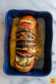 an eggplant and cheese loaf in a blue casserole dish on a marble countertop